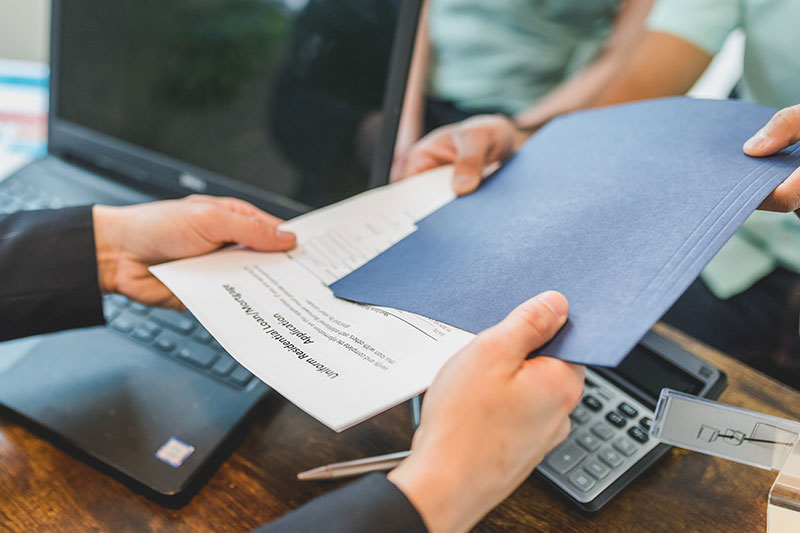 person handing over documents for a real estate referral